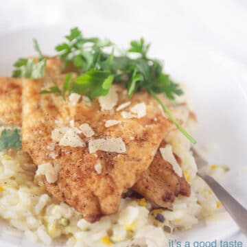 Photo of a white plate with a gold spoon. The plate is filled with risotto with zucchini and cheese. On top of that are two slices of fried cod