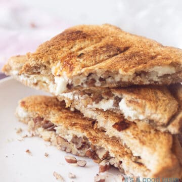 An elevation photo with a macro of three half slices of toasted sandwich filled with goat cheese, walnuts. In the background a white background and a pink white checkered tea towel
