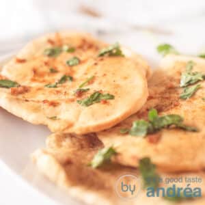 A square photo with three naan sandwiches with garlic parsley butter on a white tray on a white background