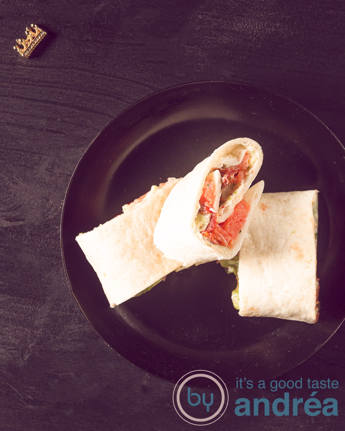 Three salmon wraps with witch cheese on a black plate with a black background