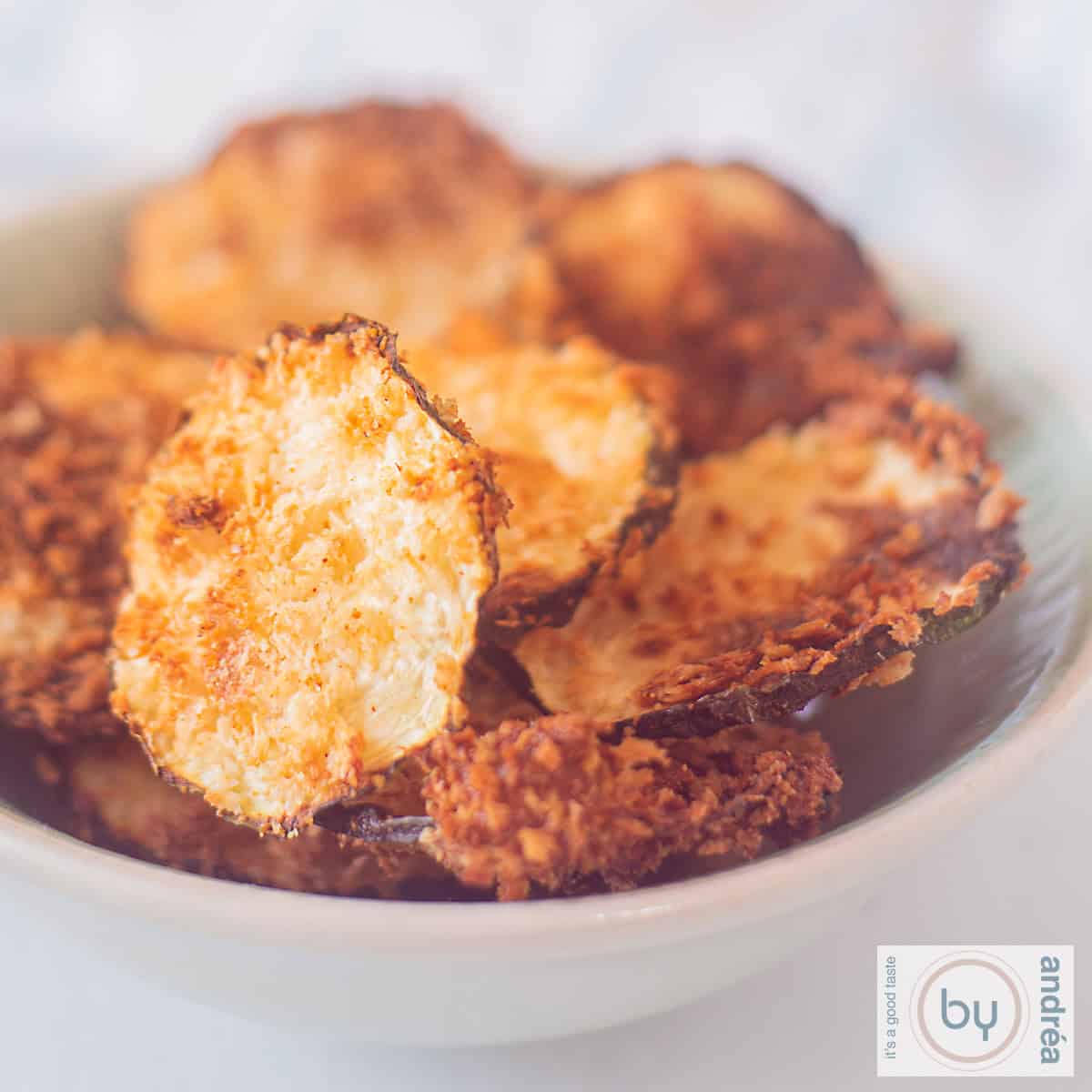 A square picture with a bowl of zucchini chips.