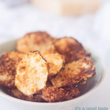 A bowl full of zucchini chips au gratin with parmesan cheese. In the background is Parmesan cheese and a grater