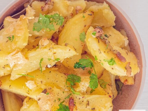 A square photo of roasted garlic potatoes with bacon, herbs and Parmesan cheese