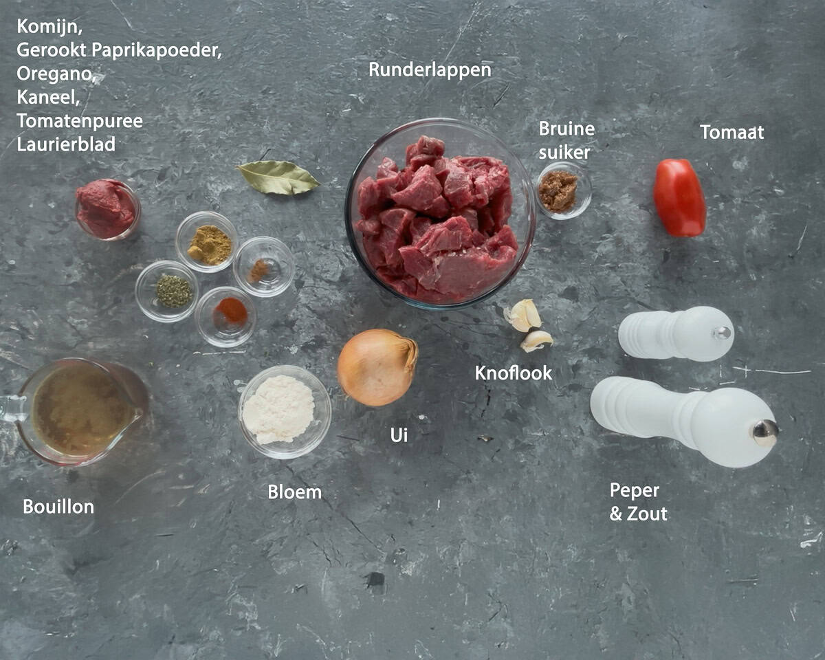 Ingredienten carne guisada Mexicaanse Runderstoofpot op een grijze ondergrond met tekst beschrijving.