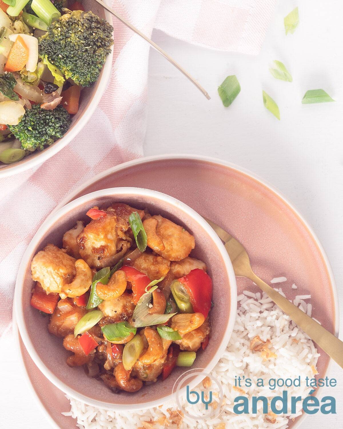 A photo from above of Thai chicken in a delicious sauce with bell pepper and spring onions. On a pink plate and that is on a white background