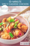 Part of a pink bowl filled with spicy cashew chicken with bell pepper. A text on top: Easy Recipe, 15-minute spicy cashew chicken