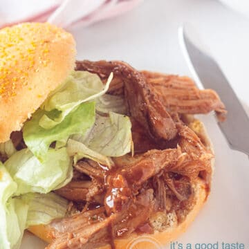 A white background, on top of which a sandwich with BBQ pulled pork and a salad. A knife right next to it, a white background