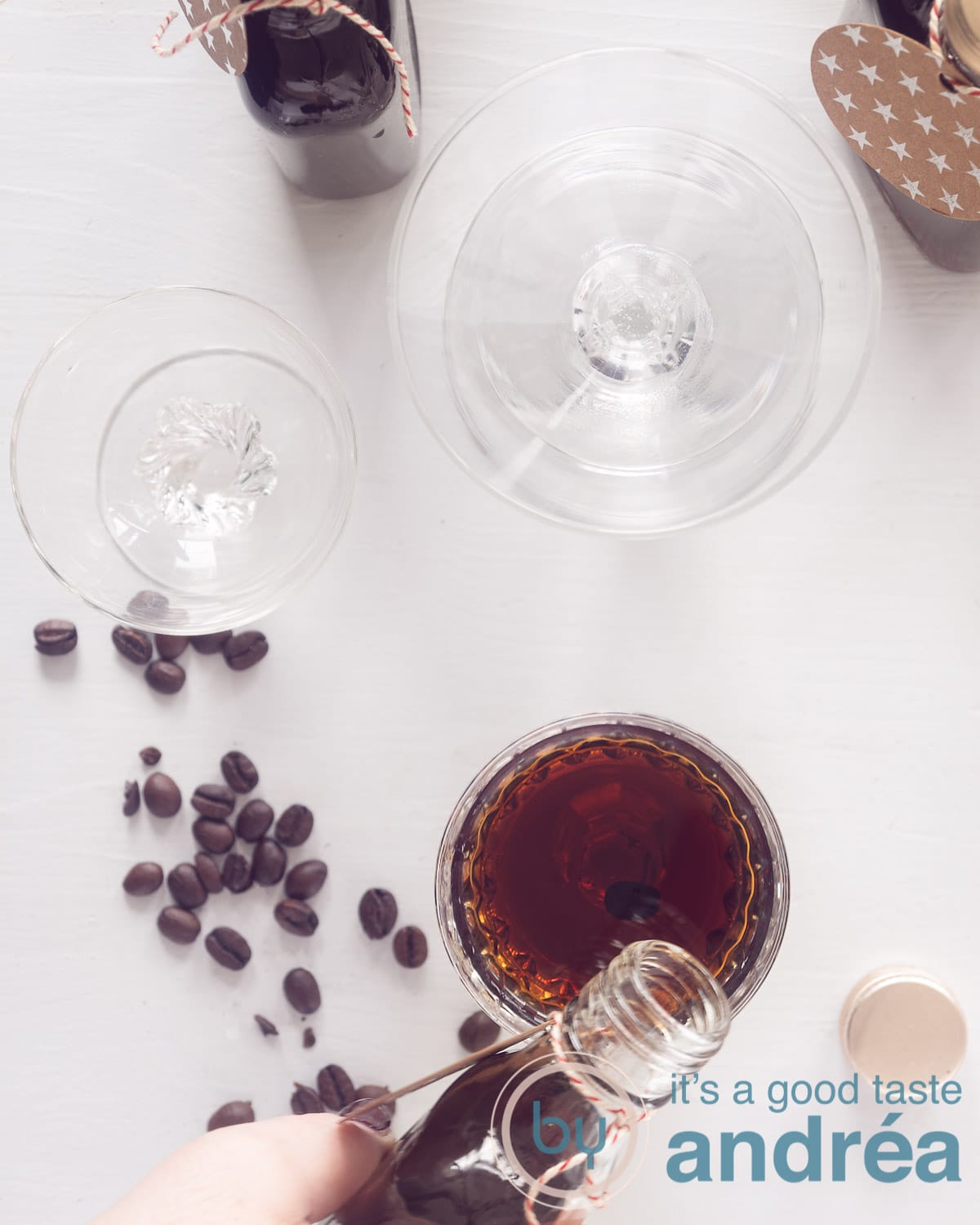 A photo from above showing three glasses, the first being filled with coffee liqueur. Some coffee beans on the white background