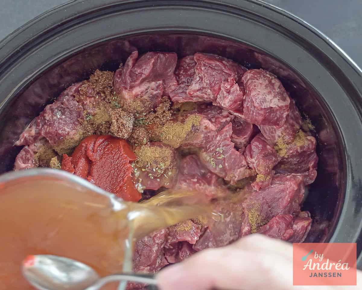 Meat, herbs, and seasonings in the slow cooker. Add the broth.