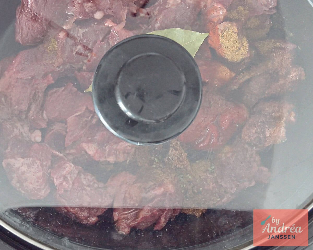 Lid on the slow cooker filled with the ingredients for a Mexican stew