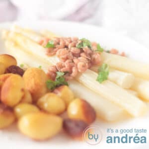 A square picture of a white plate with potatoes asparagus, shrimp butter sauce