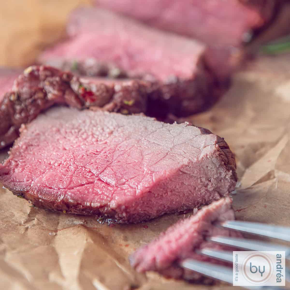A square photo with slices of roast beef on baking paper with a piece cut off