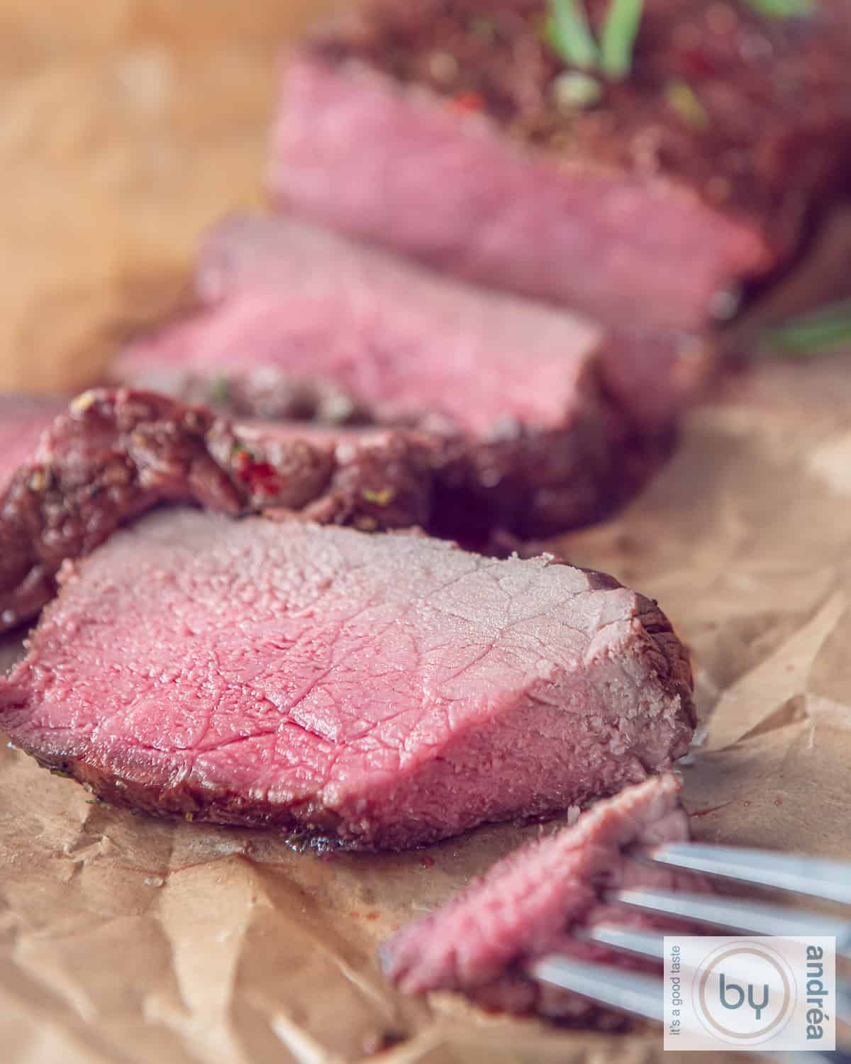 A piece of roast beef from which three slices have been cut.