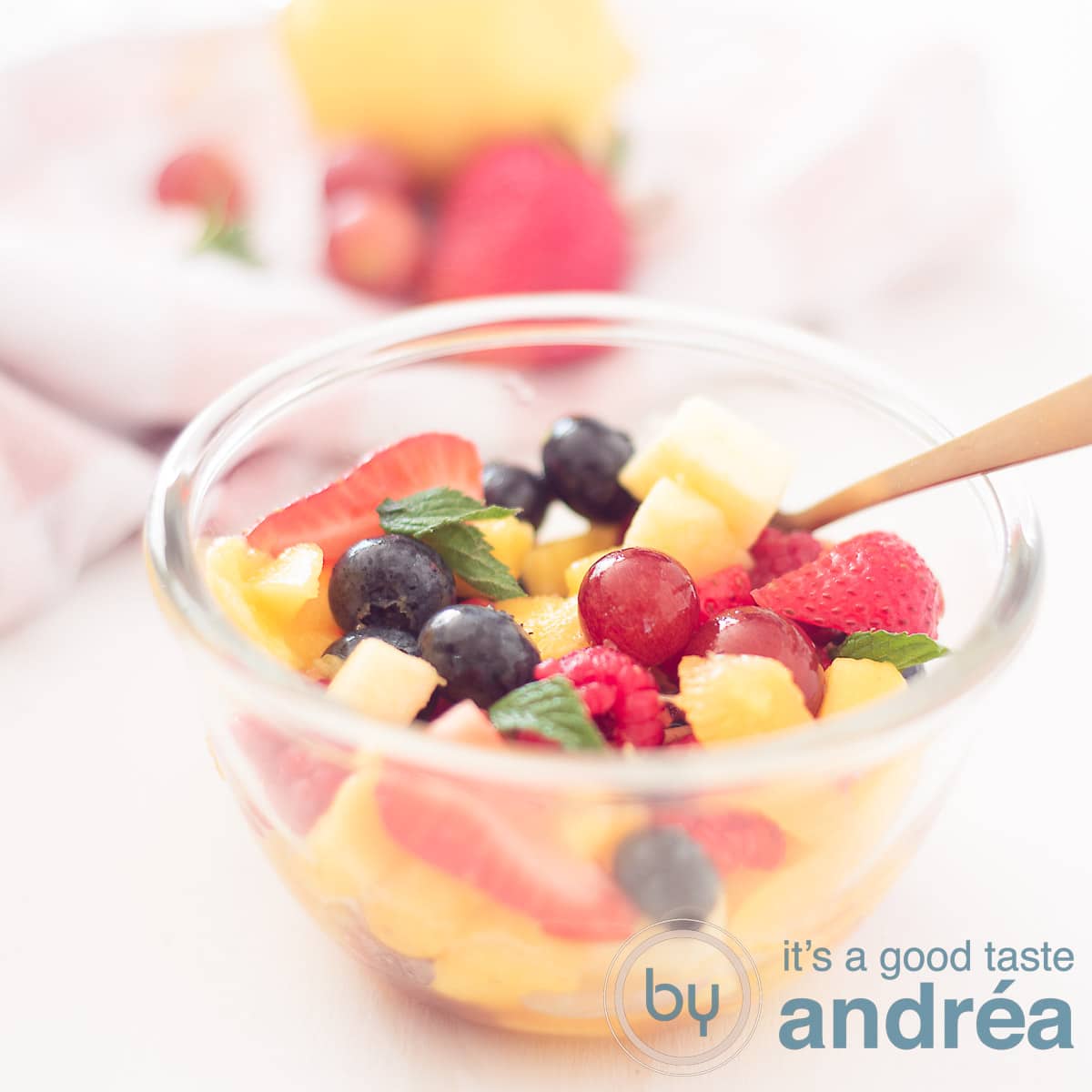 A square photo with a fresh fruit salad on a white background. Fresh fruit in the background