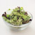 Green mixed salad in a glass bowl on a white background