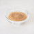A glass bowl filled with cane sugar on a white background