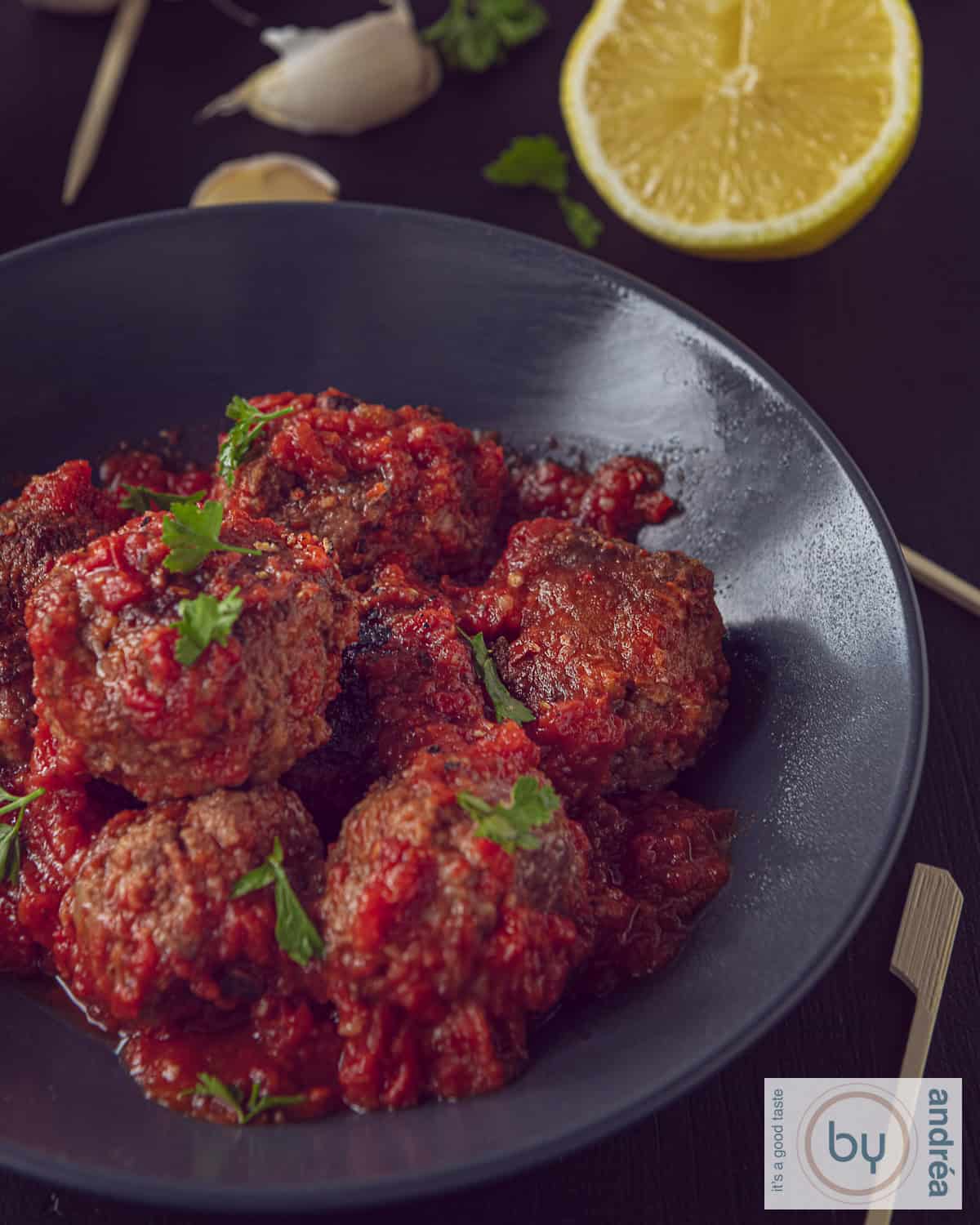 A gray bowl with albondigas, Spanish meatballs in tomato sauce.