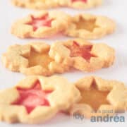 A square photo with six cookies filled with candies to make them look like stained glass. Two by two (red and yellow filling) on top of each other on a white background.