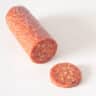 Een chorizo worst waar een plakje vanaf is gesneden op een witte ondergrond
