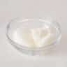 A glass dish filled with lemon sorbet ice cream on a white surface