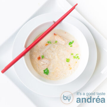 A square photo with a white background, a square plate, a round plate and a white soup bowl filled with creamy chicken soup. Two red chopsticks lie on it.
