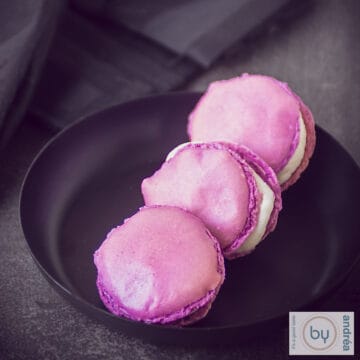 Pomegranate macarons with Champagne on a black plate