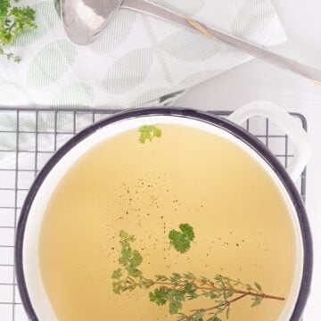 Homemade vegetable stock in a bowl with some herbs