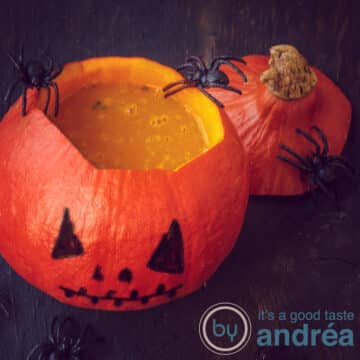 an orange pumpkin filled with pumpkin soup and spiders