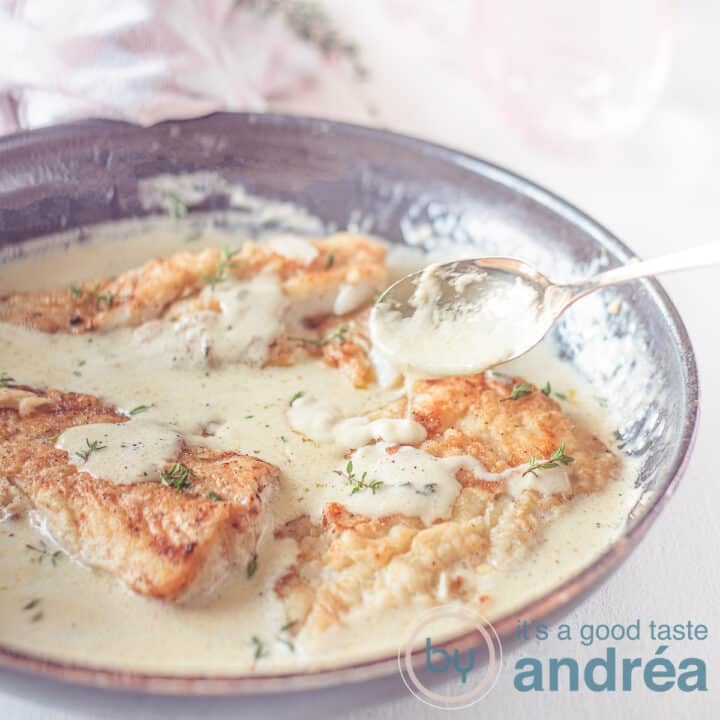 A square photo with a skillet filled with cod and a creamy white wine lemon sauce.