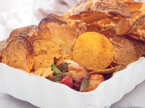 a square photo of a chicken casserole topped with nachos and tortilla's