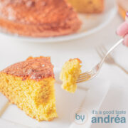 A part of an orange cake. A fork taking a bite of it.