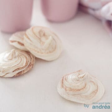 A white background with winter meringues. In the back two pink cups.