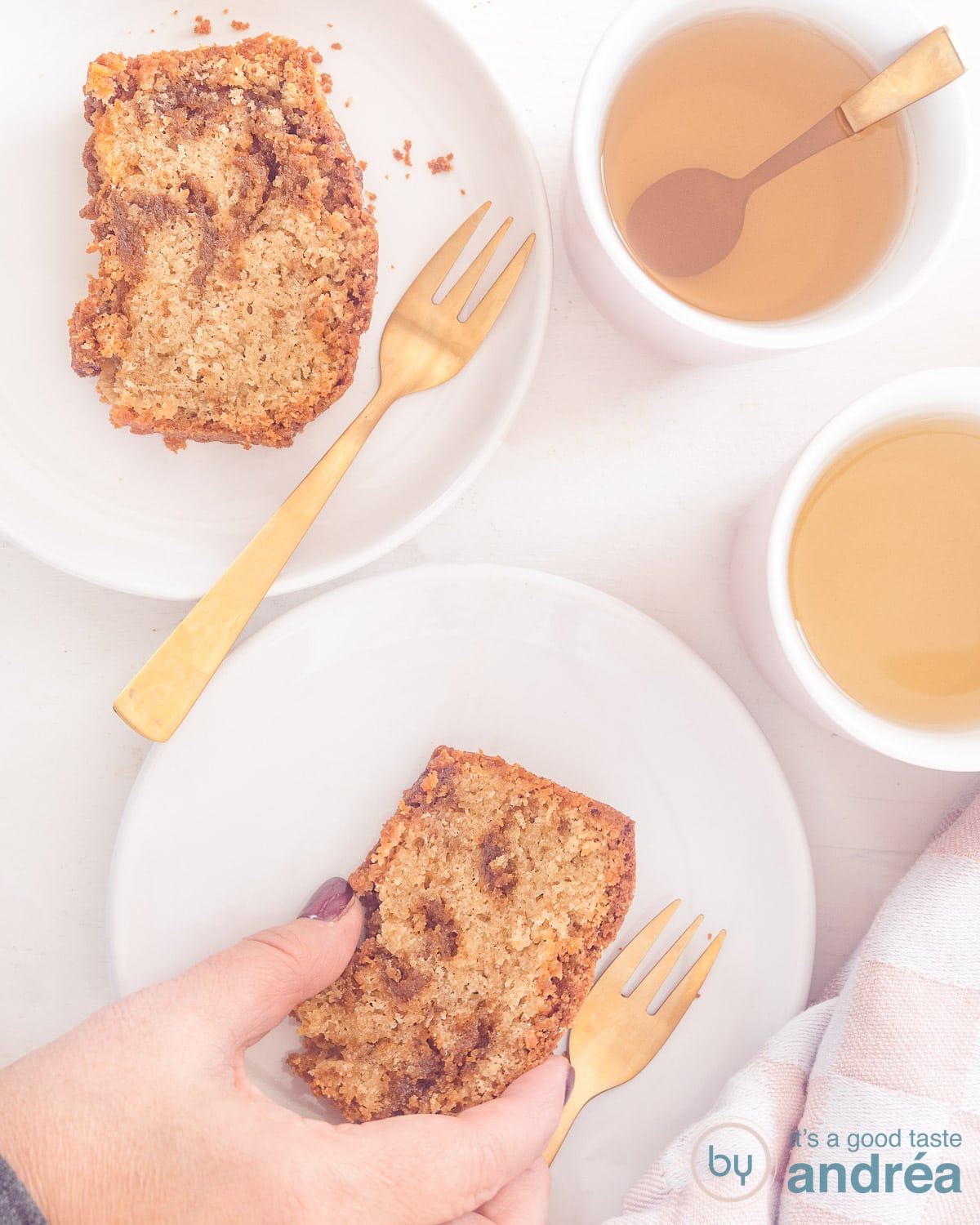 Two white plates with slices of stroopwafel cake, cups of tea next to them. A hand grabs the cake.