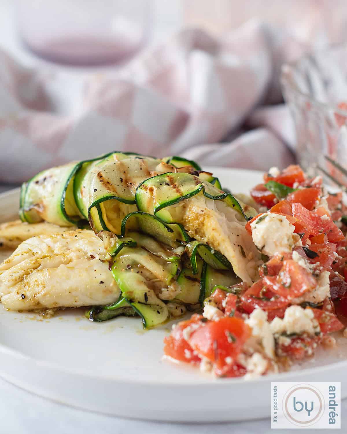 Tilapia filet, fried, with tomato salad on a white plate