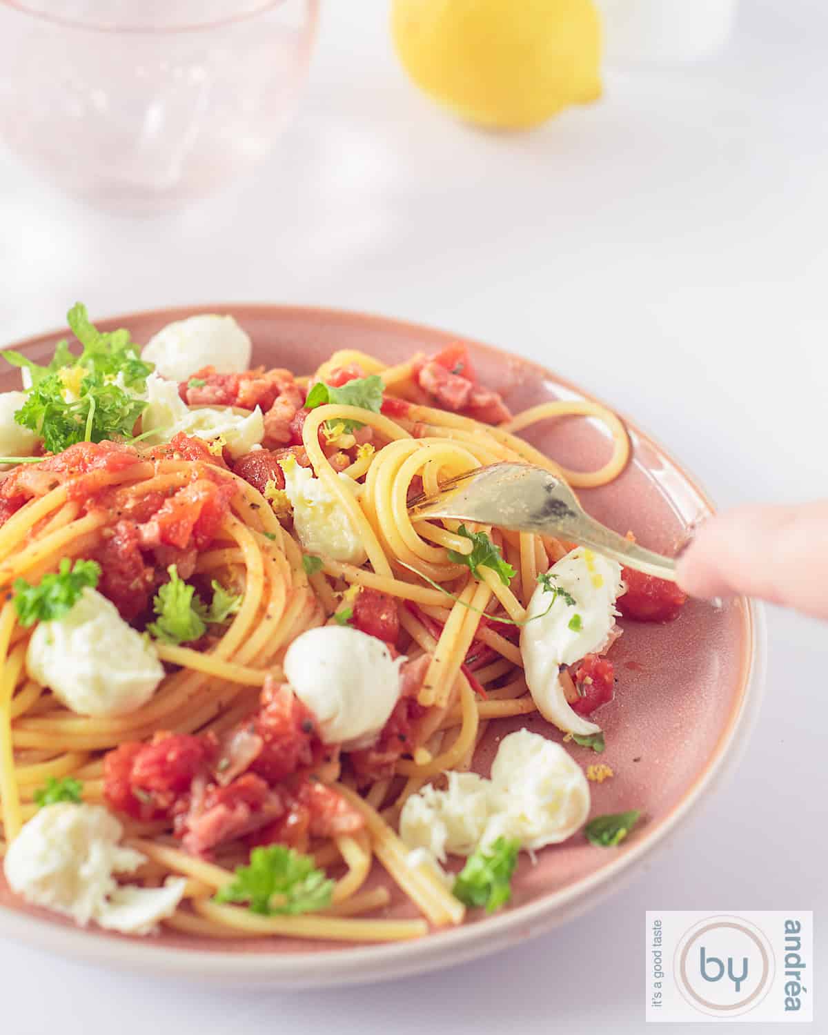 A pink plate with spaghetti, tomatoes, mozzarella and bacon.
