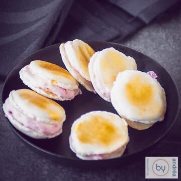 Vanilla macarons with Prosecco strawberry filling on a black plate