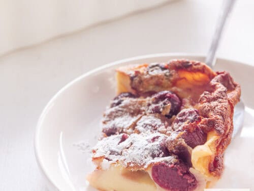 A square picture of a white plate with cherry clafoutis