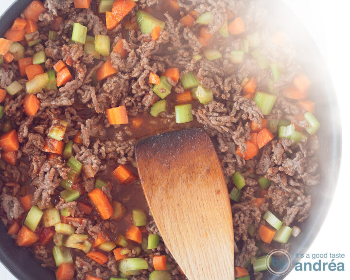 A skillet filled with fried ground beef, carrots and celery.