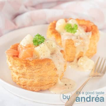 A square photo with a white plate with two trays filled with smoked salmon and asparagus ragout that drips over the tray. A golden fork is there.