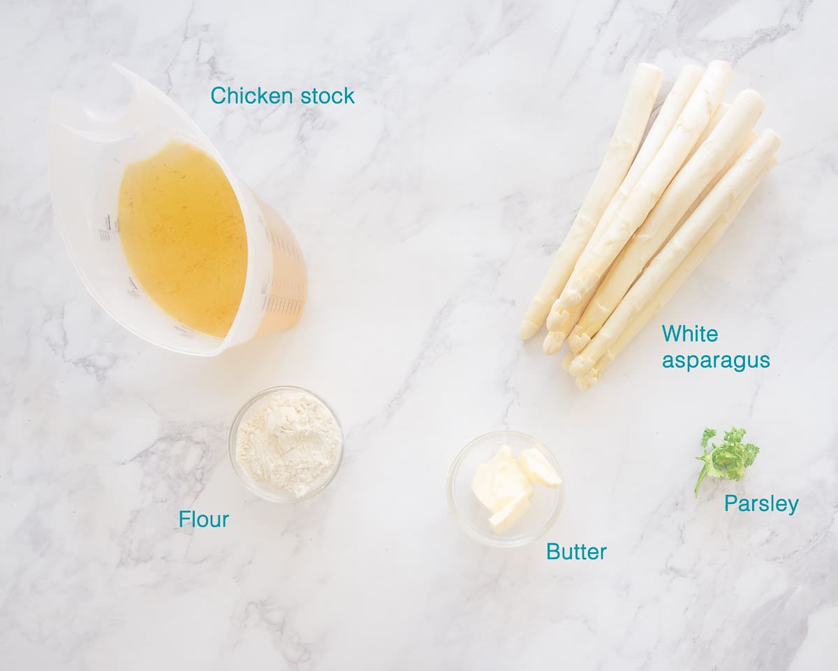 Ingedients Spargelsuppe (Creamy Asparagus Soup), five ingredients individually labelled on a white marbled background