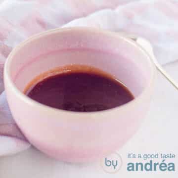 A square photo of a pink bowl filled with homemade tonkatsu sauce. A golden spoon is next to it. In the background a pink and white tea towel.
