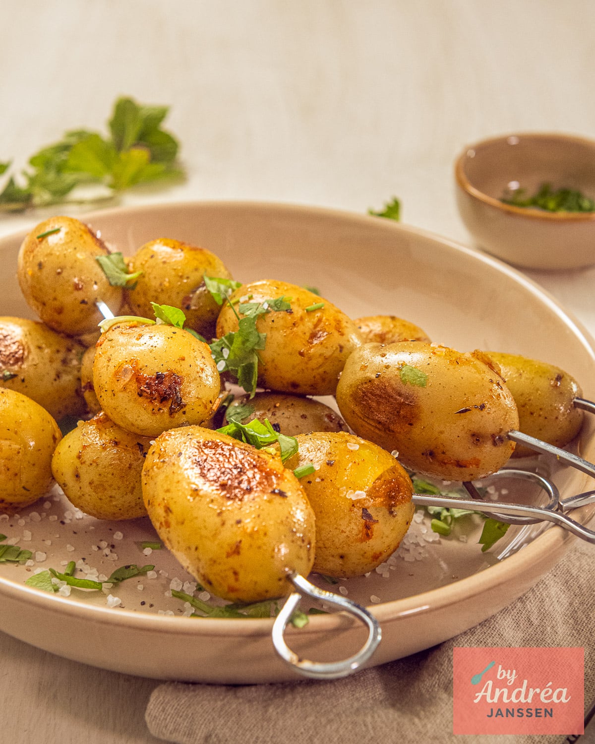 Crispy BBQ baby potatoes on skewers with golden grill marks, sea salt, and fresh herbs.