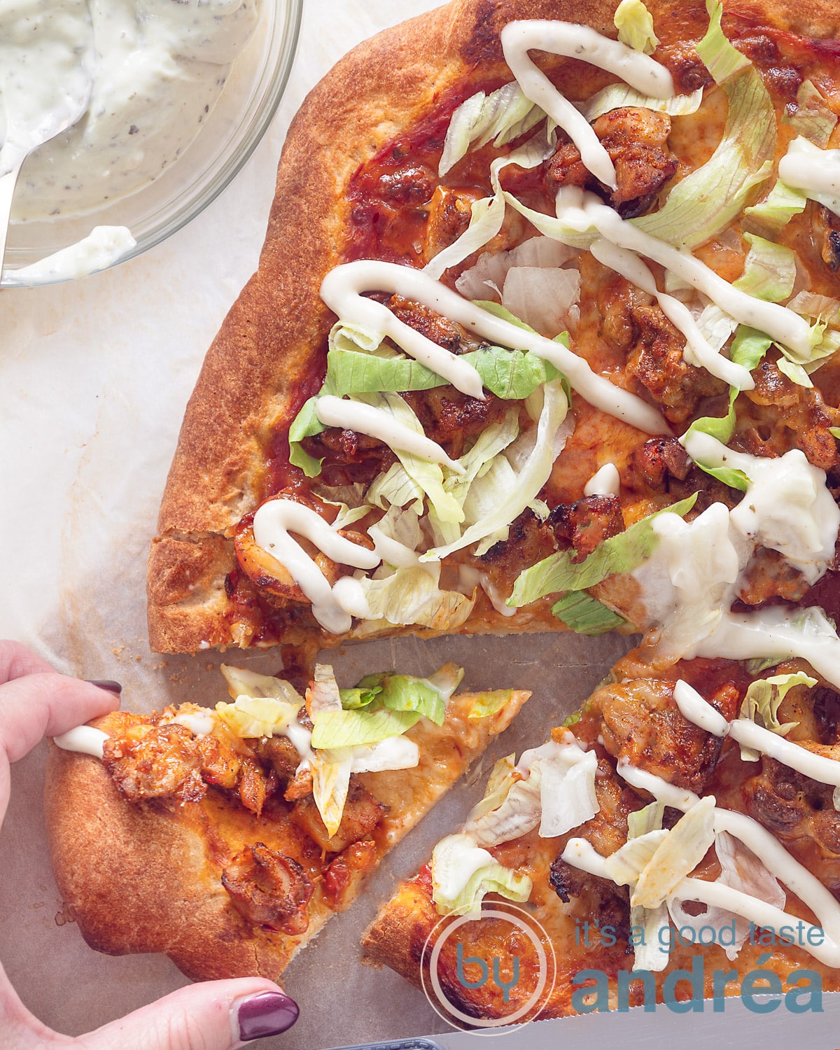 An elevation photo with a pizza with chicken doner, iceberg lettuce, garlic sauce on a white background. Cut out a triangle that is packed away.