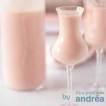 A square photo with a liqueur glass filled with a homemade strawberry cream liqueur. A bottle on the right. A white background