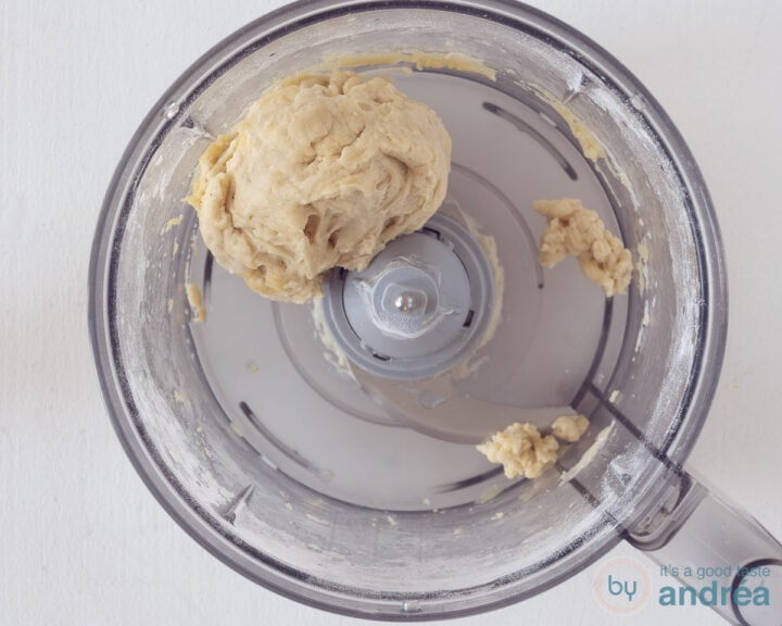 The bowl of a kitchen machine with a ball of dough