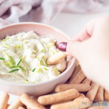 A square photo with gorgonzola dip, where a stick takes out a scoop. Sticks lie around it.