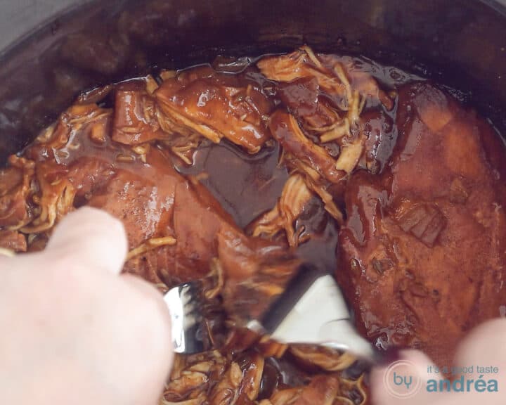 A slow cooker in which the chicken is pulled apart with two forks