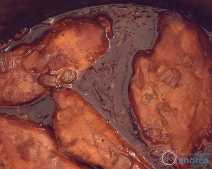 A slow cooker filled with chicken fillets in a BBQ sauce.