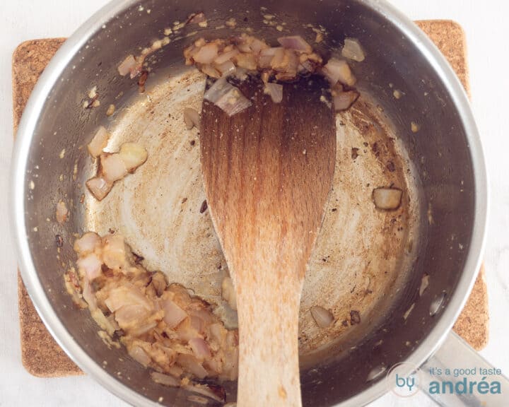 A saucepan containing a fried onion and garlic.