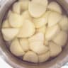 A pan filled with peeled potatoes and water.